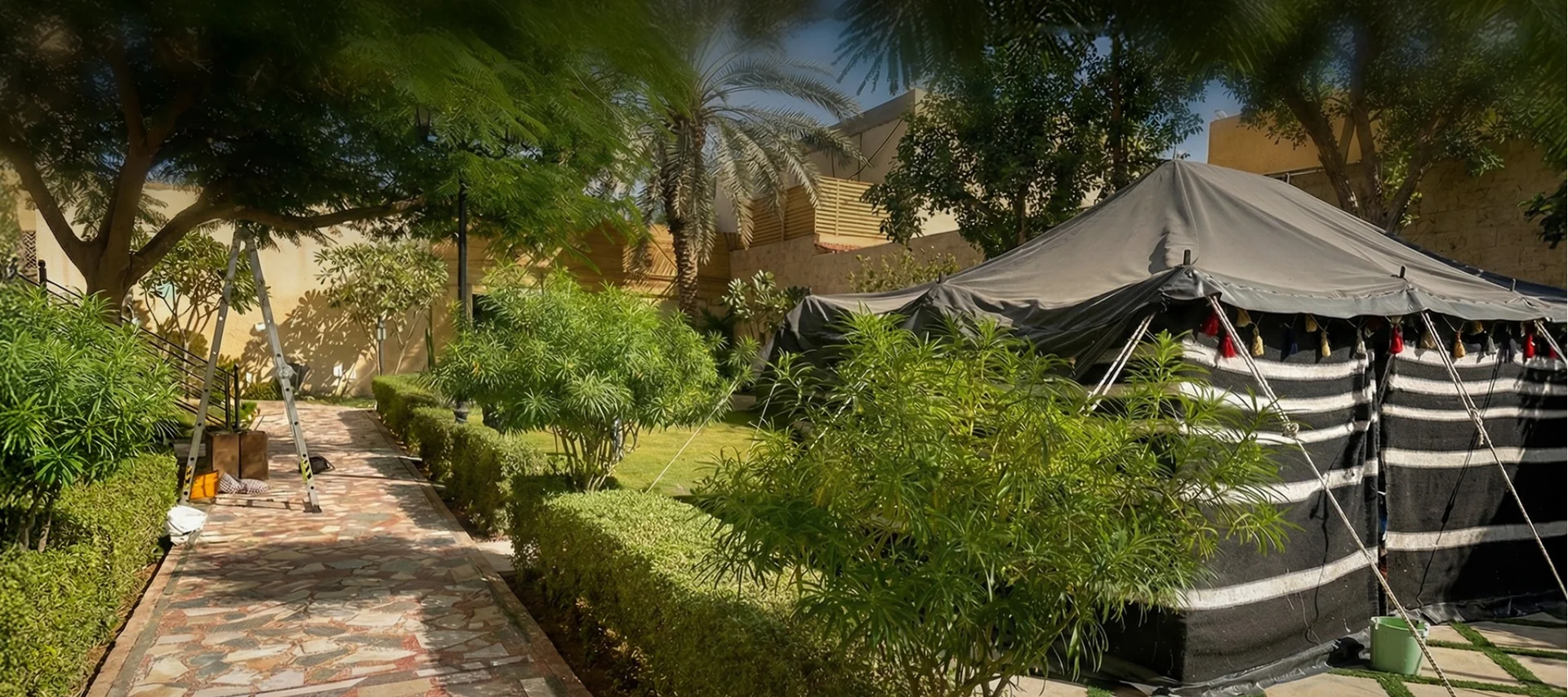 Shaded garden with a patterned path, planted borders and a tent